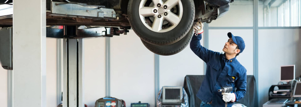 mechanic checking the bottom of a vehicle