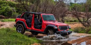 red 2025 jeep wrangler crossing a creek